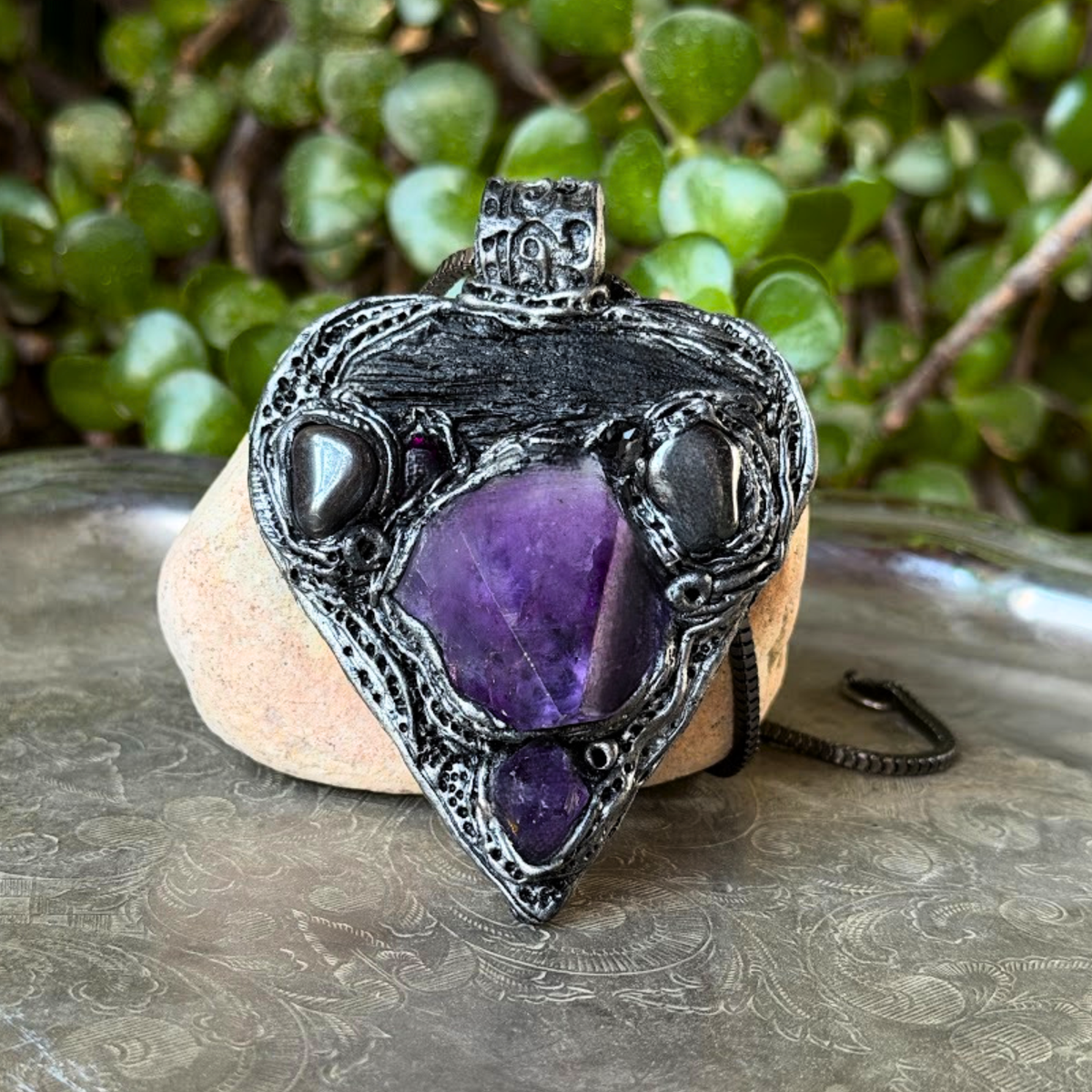 Sculptural heart pendant necklace with central purple Amethyst, dark textured setting and polished Hematite stones.