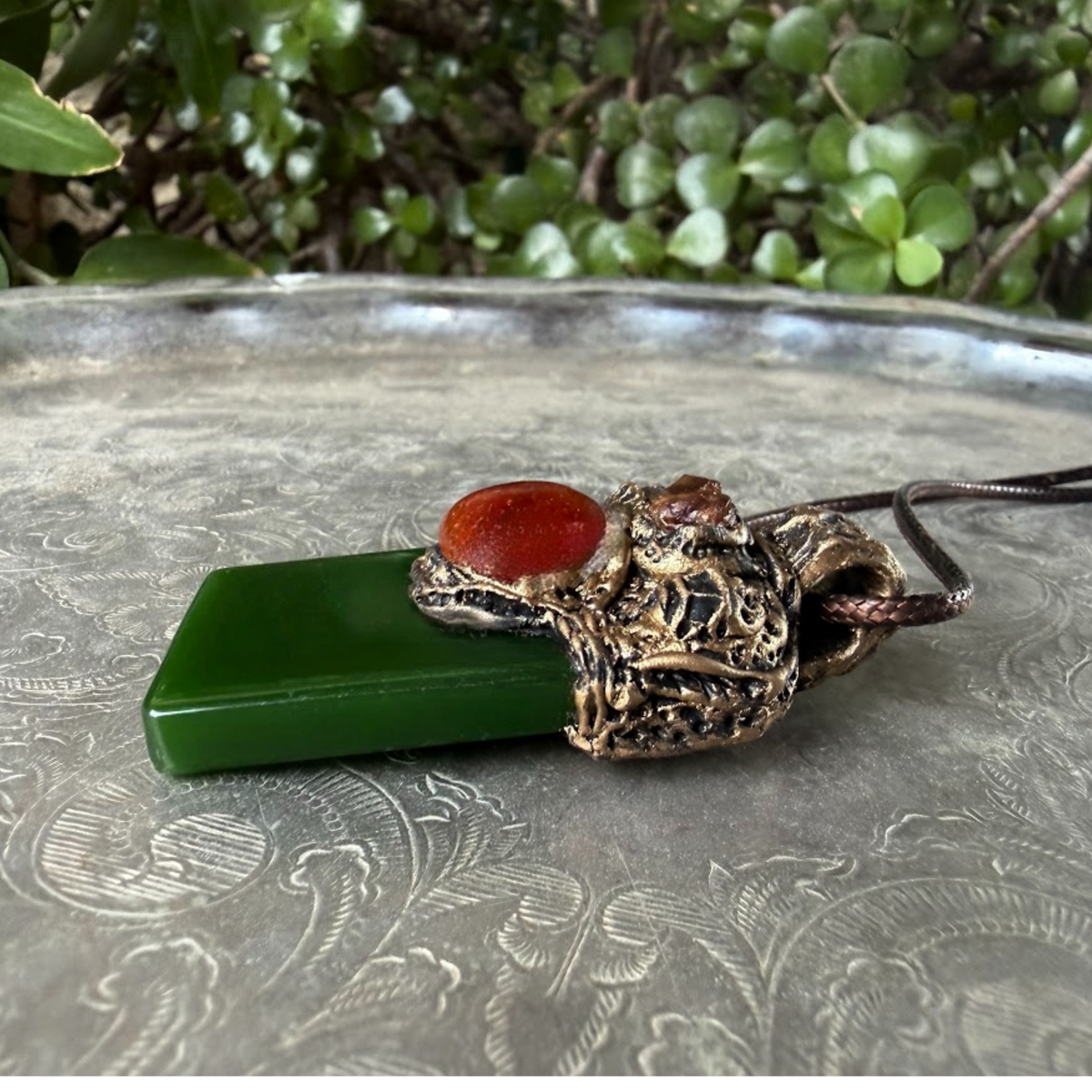 Large green Jade pendant necklace with red Carnelian stones in a handcrafted sculptural amulet setting.