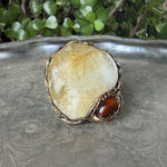 Oversized Citrine and Carnelian statement ring with a large pale yellow natural crystal and smaller reddish-brown stone in a sculptural setting.
