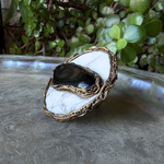 Large round Hawk’s Eye and white Howlite statement ring with a horizontal dark stone in a handcrafted sculptural setting.